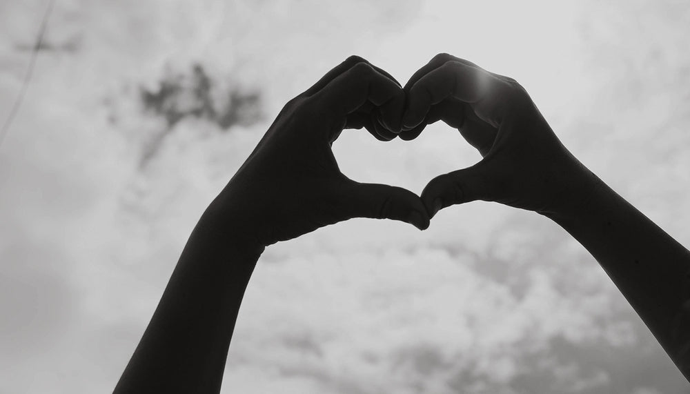 Hands in the air making a love heart shape with fingers