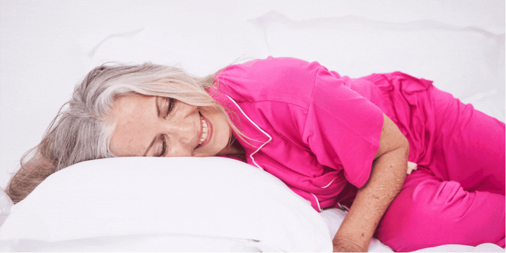 model wearing pink pyjamas lying on bed